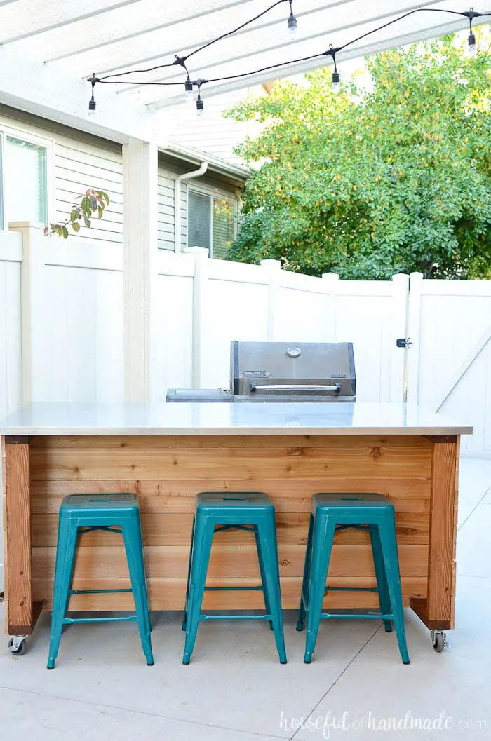 Seating at an outdoor kitchen with bar stools and a grill. 