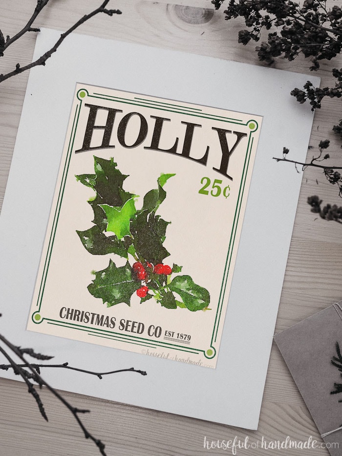 Holly printable Christmas art in a white mat on the table.