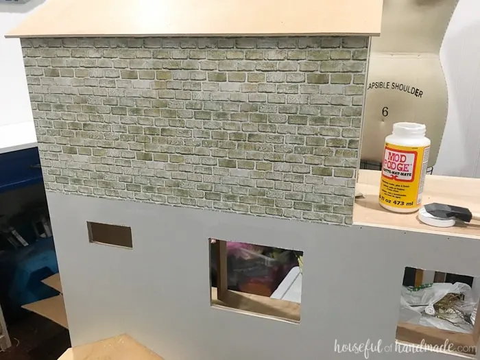 Add faux brick to the dollhouse exterior with Mod Podge. It looks fantastic and is budget friendly. Housefulofhandmade.com