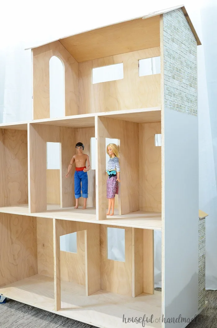 large handmade dollhouse shown with two barbie dolls shown inside