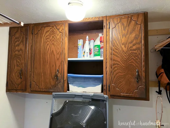 Before photo of the farmhouse laundry room reveal. Old kitchen cabinets in the laundry room with one door missing. Housefulofhandmade.com