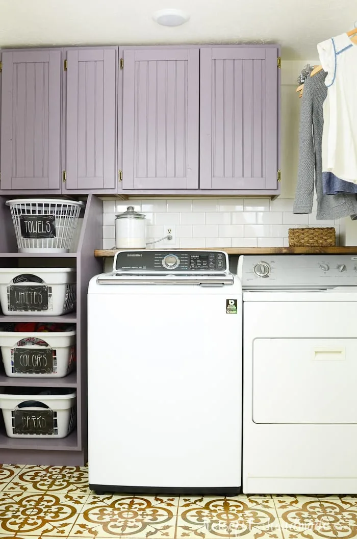 Farmhouse laundry room closet with stackable laundry basket storage and purple painted cabinets. Housefulofhandmade.com
