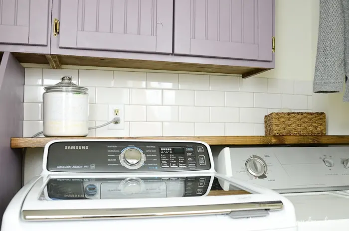 Farmhouse laundry room with a subway tile backsplash behind the barnwood shelf. Housefulofhandmade.com