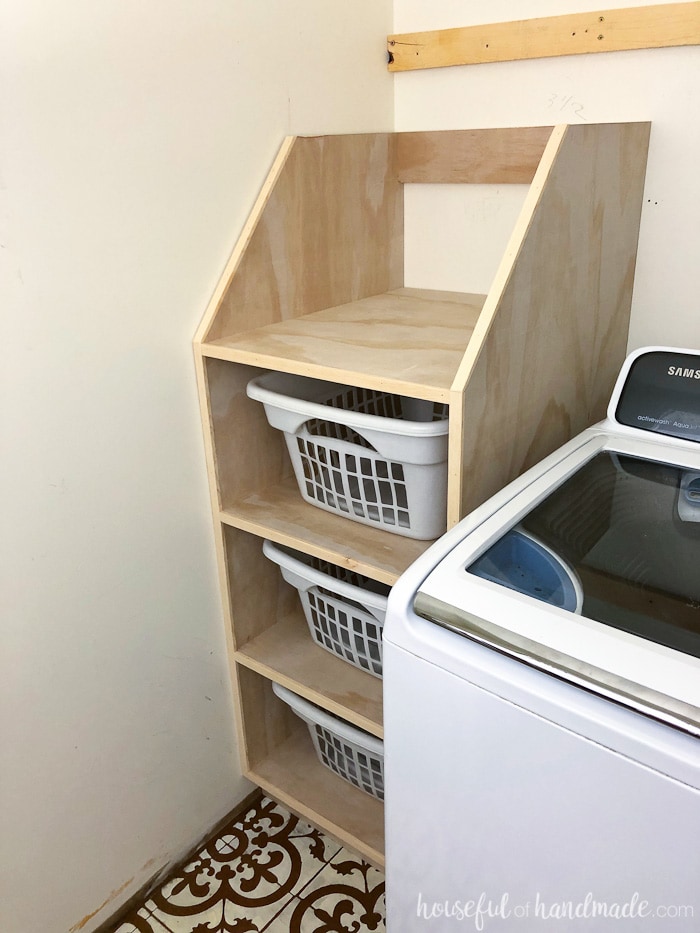 Stackable laundry basket organizer shown on side of washing machine. 