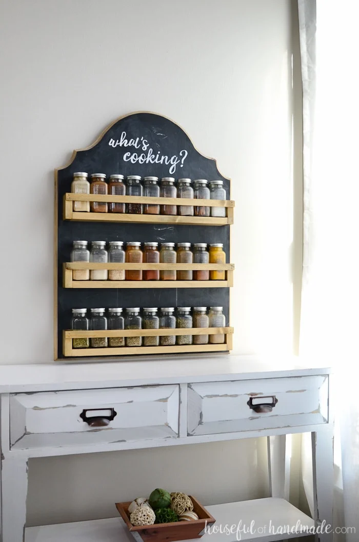Hanging spice rack shown hanging on wall with glass spices 