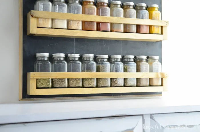 Large DIY spice hung on wall filled with glass spice jars 