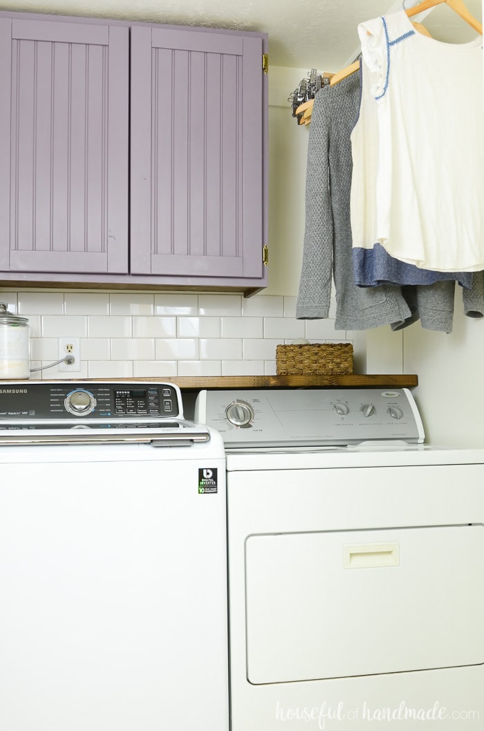 Laundry room with hanging clothing and purple cabinets that we were able to build cabinet doors cheap for! Housefulofhandmade.com