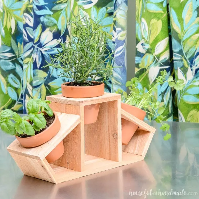 DIY countertop herb garden made with a cedar fence picket and 3 clay pots. 