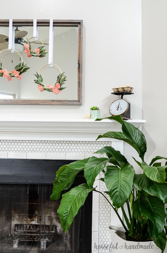 Simple mantel decor for spring consists of floral embroidery hoop wreaths hung on a gray rustic mirror. Housefulofhandmade.com
