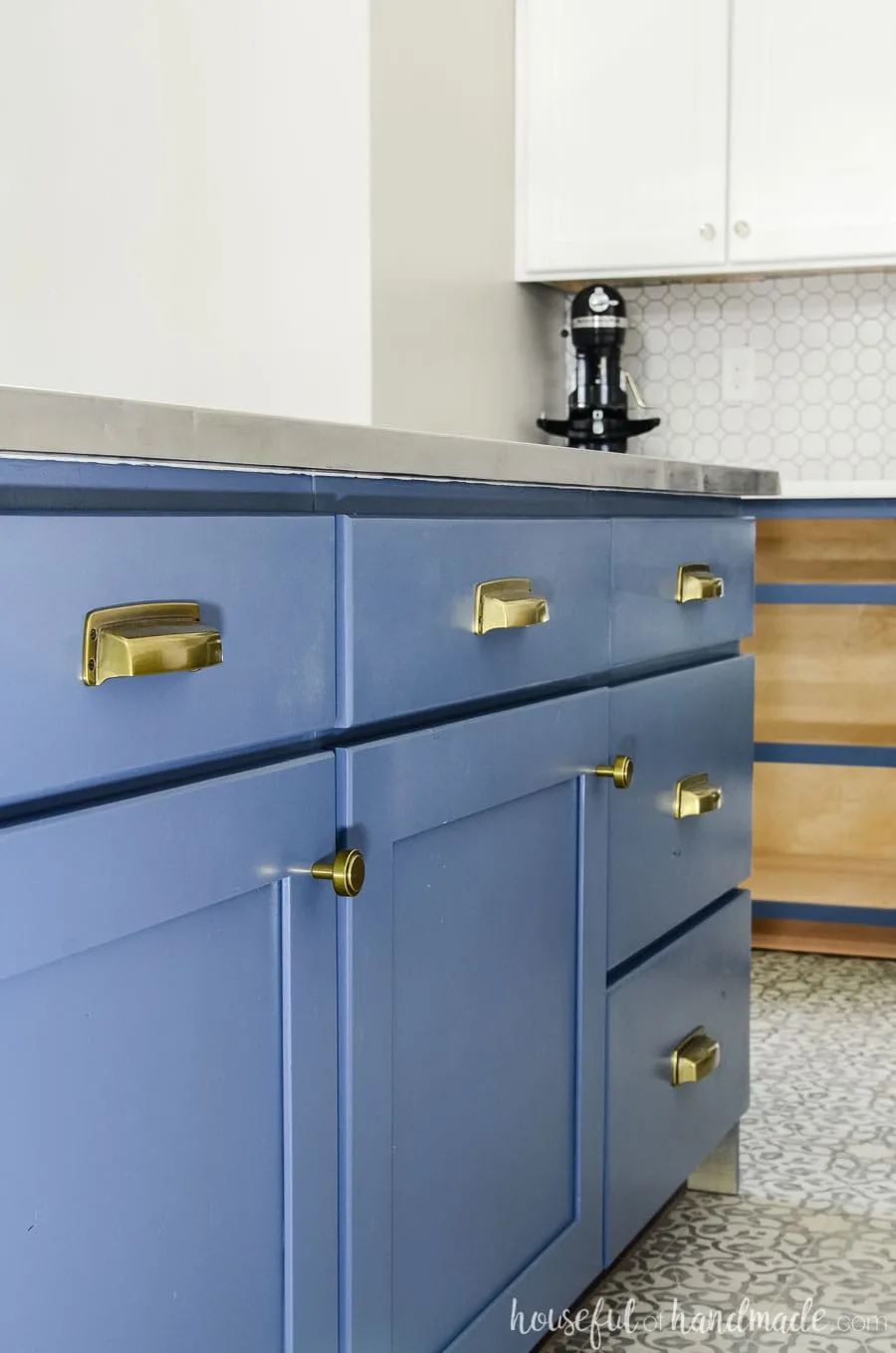 Brass knobs and pulls are perfect on the navy blue base cabinets. See the complete budget farmhouse kitchen remodel at housefulofhandmade.com.