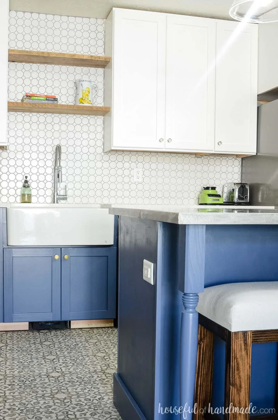 Gorgeous white and gray navy kitchen with textured white porcelain tile. Rustic floating shelves and a farmhouse sink are perfect for a budget farmhouse kitchen remodel. Housefulofhandmade.com