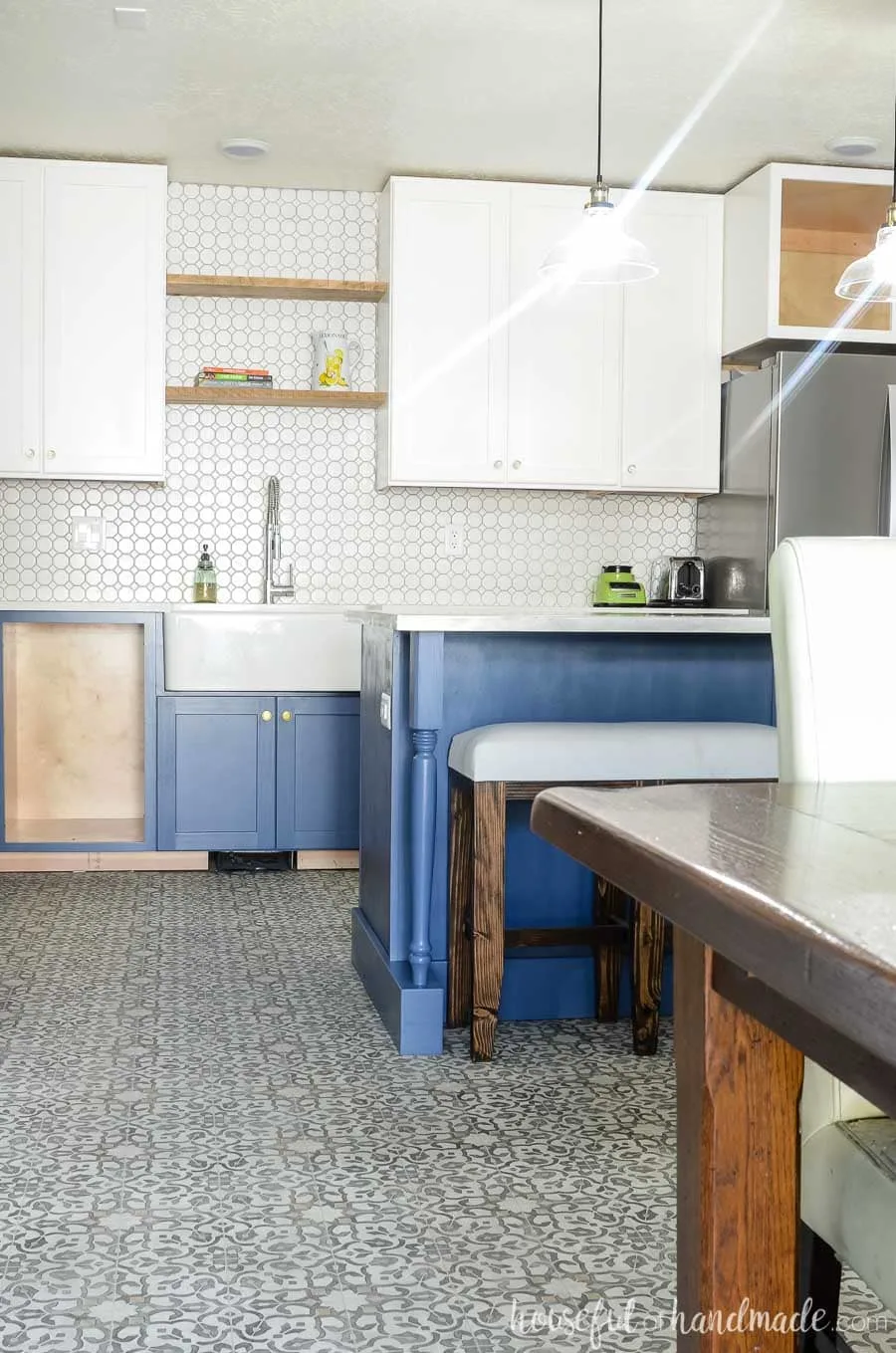 Stunning white and navy farmhouse kitchen. The kitchen island looks like a piece of furniture in the center of the kitchen and the open shelves above the farmhouse sink keep the space bright and open. Housefulofhandmade.com