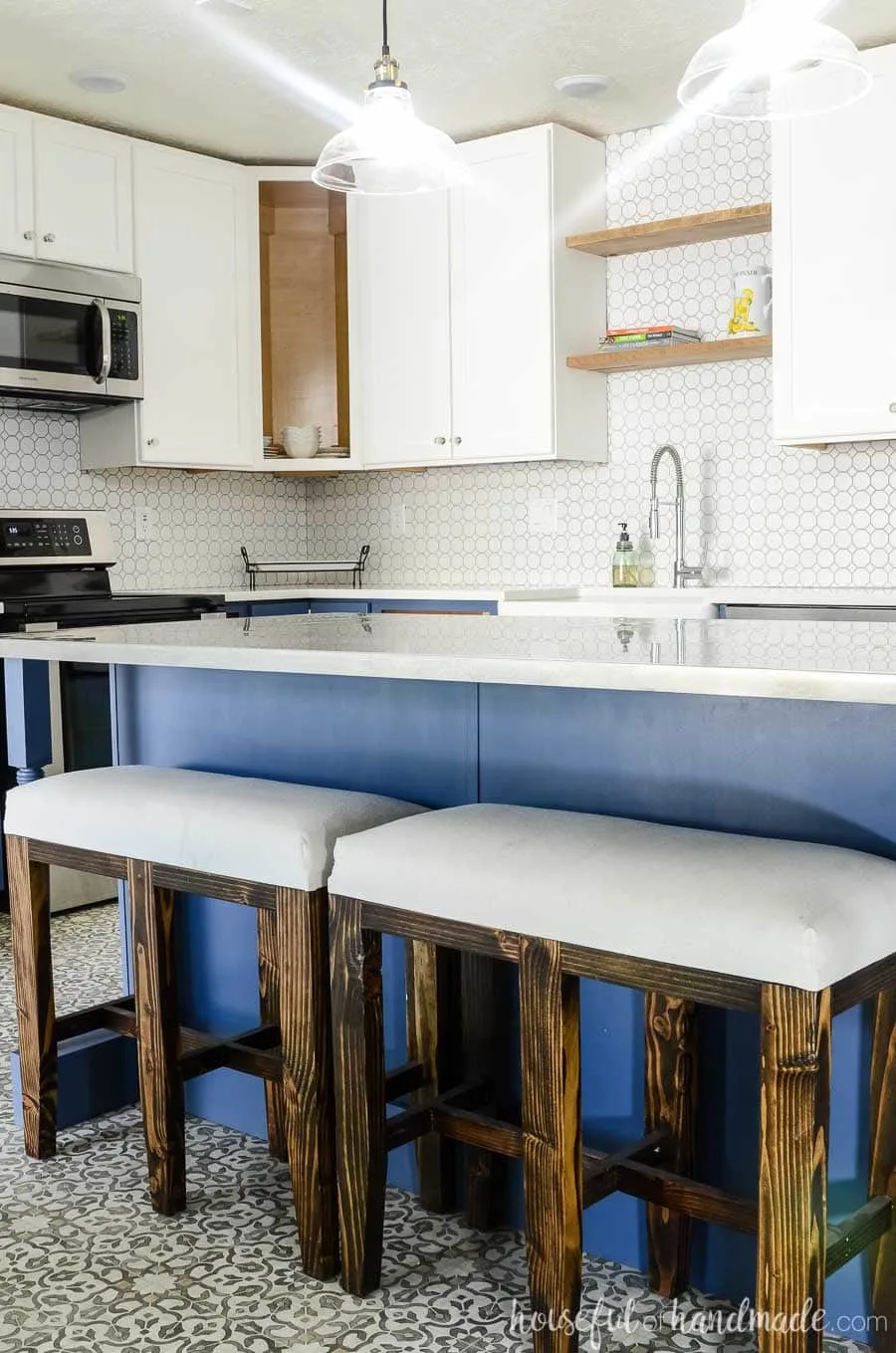 Navy blue kitchen island with rustic bar stool benches are the perfect centerpiece for this budget farmhouse kitchen remodel. Housefulofhandmade.com