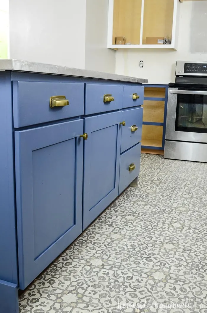 Brass hardware on a soft navy kitchen island with 3 cabinets with cabinet doors and drawer fronts. 