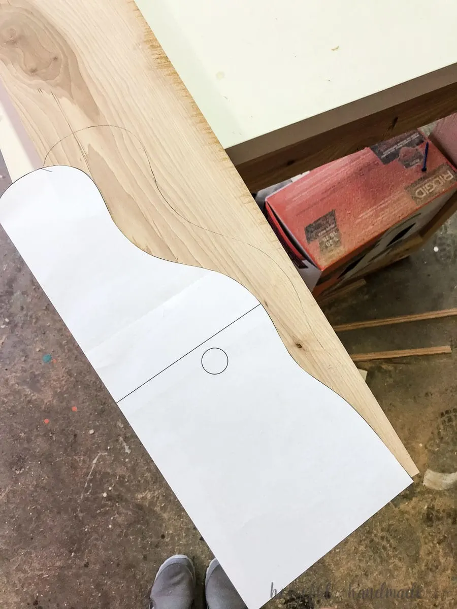 Printed template being traced onto the 1x6 board to create a farmhouse paper towel holder.