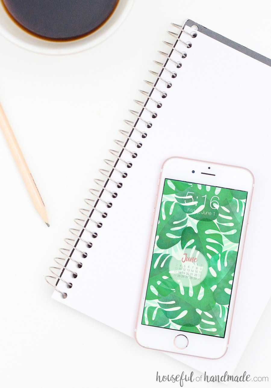 iPhone on a notebook displaying watercolor leaf digital background and calendar. 