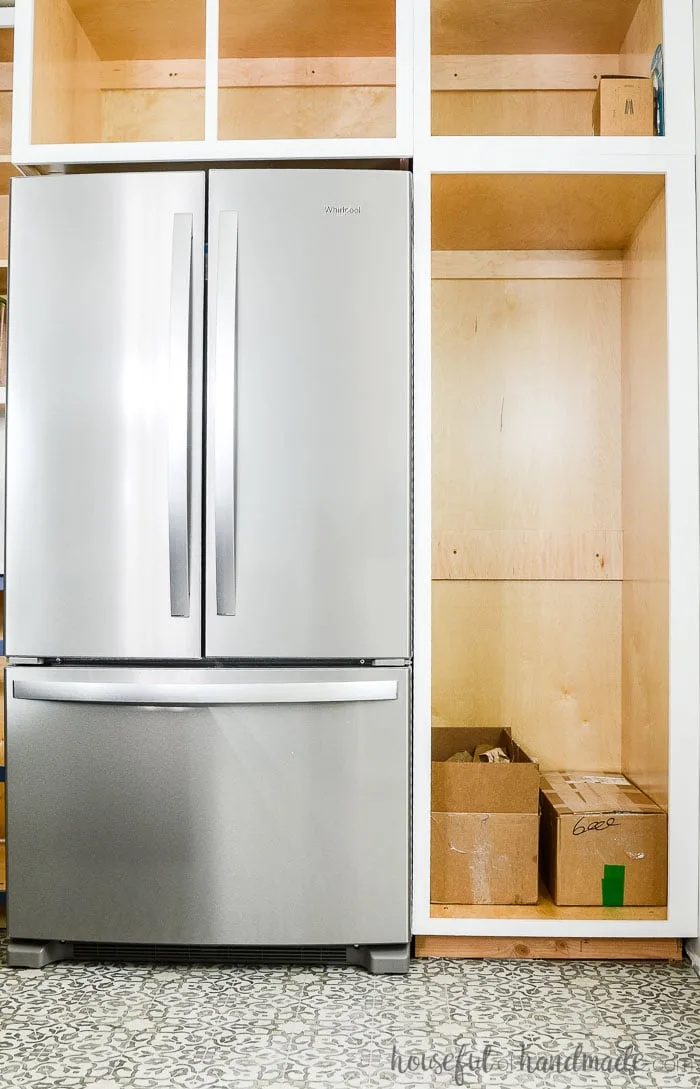 White painted face frames with the new stainless steel French door refrigerator. See how to paint unfinished cabinets at Housefulofhandmade.com.