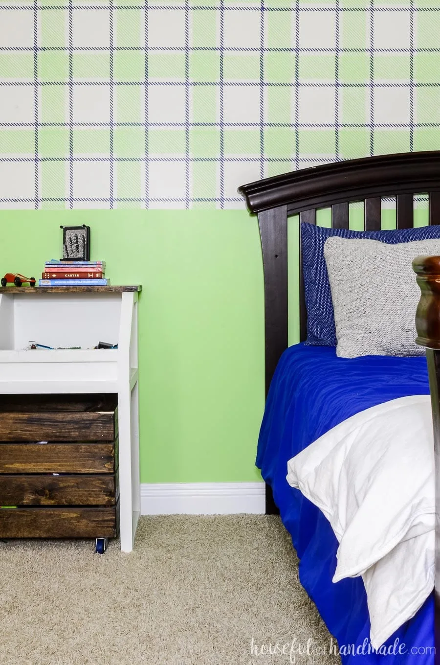 Boys bedroom with blue & green plaid wall design. Rustic toy storage console and arched headboard bed frame in front of wall. 