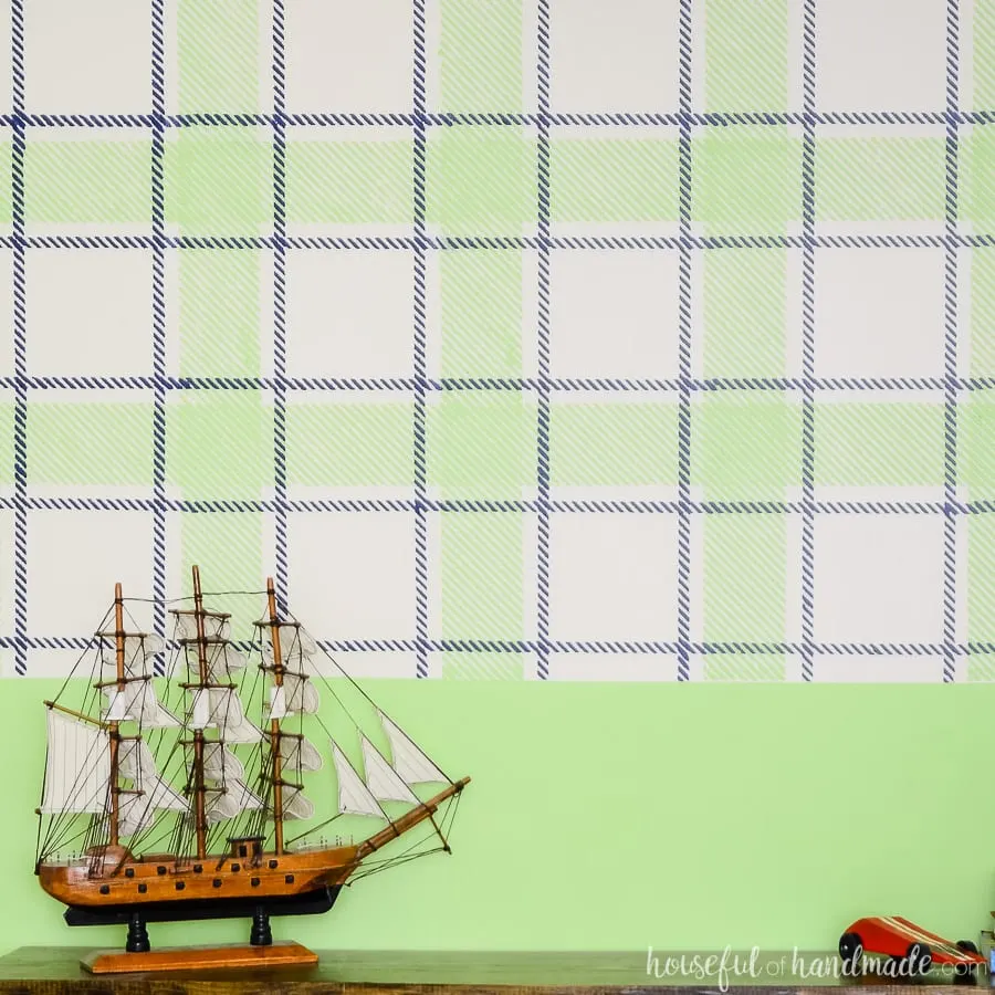 Toy pirate ship on top of the toy console in front of a navy & green plaid wall design. 