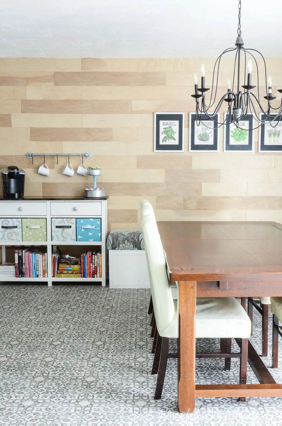 Dining room with black chandelier and wood accent wall. Large rustic table and white coffee station.