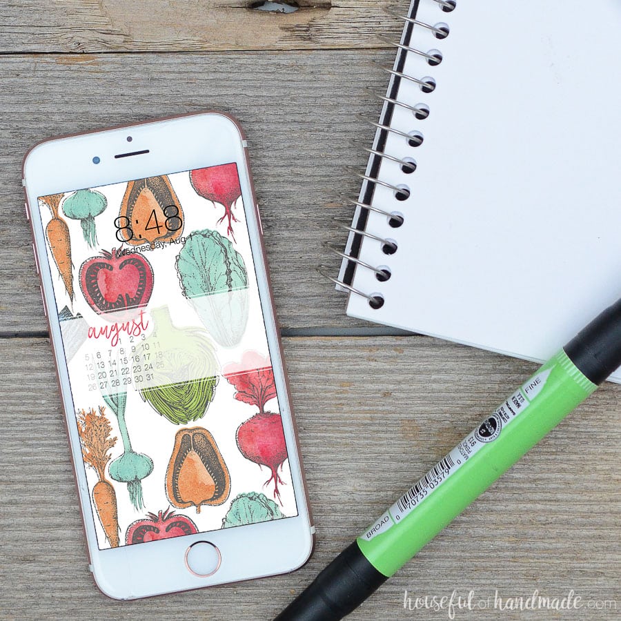 Bring the farmers market to your screens with these beautiful free digital backgrounds for August. The watercolor vegetable pattern is the perfect way to decorate your electronics for the last days of summer. #digitalbackground #digitalwallpaper #vegetableart #freedownload Digital background with August calendar. Free digital wallpaper of colorful hand-drawn vegetables on a smartphone screen next to sketchbook.