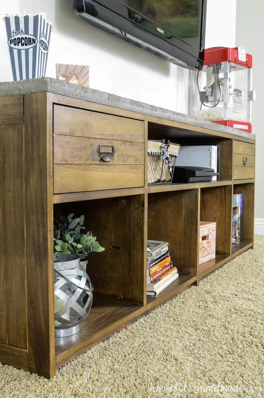 Angled view of medium brown stained TV stand with 2 drawers and a concrete top.