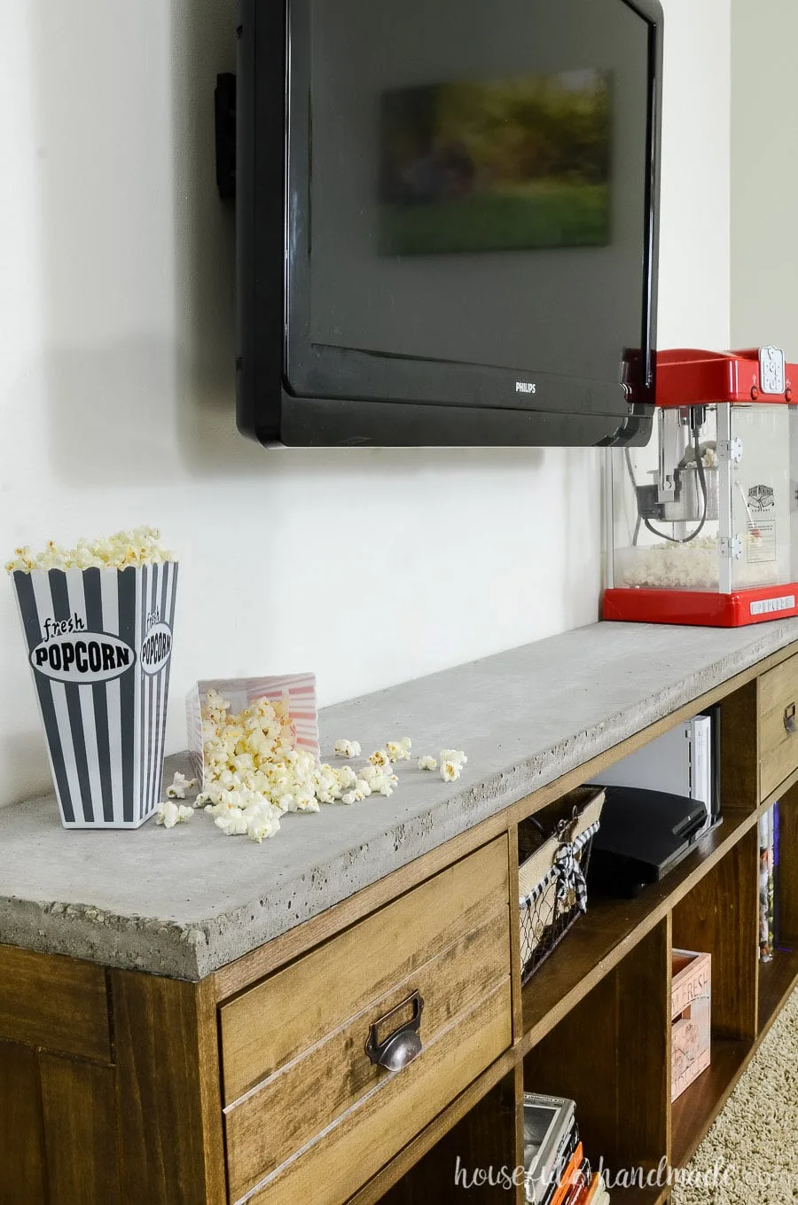 Close up of the concrete top on the rustic TV stand. Styled with popcorn popper and popcorn containers. 