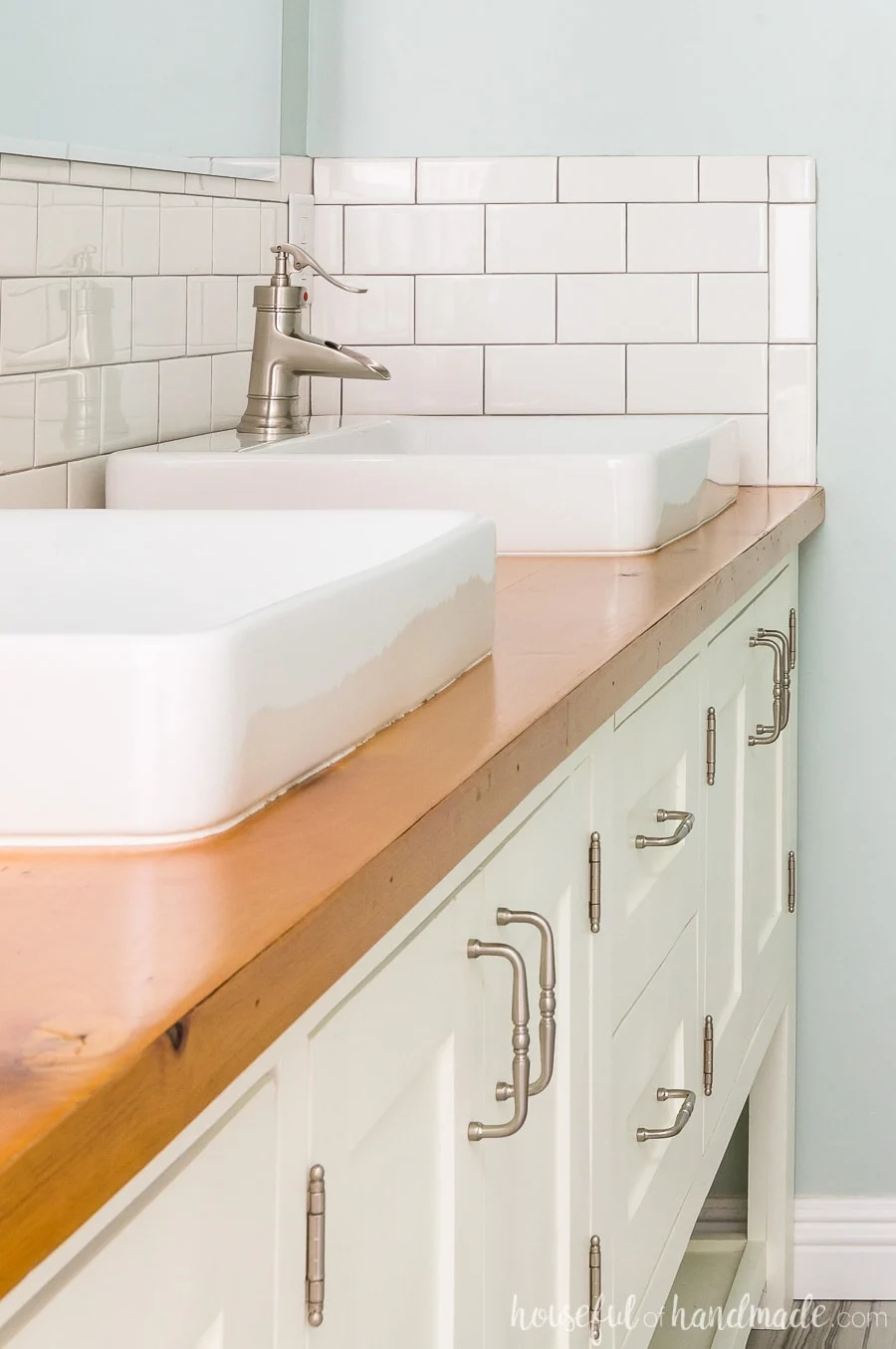 Two large vessel sinks on top of a natural wood vanity top make this a master bathroom retreat. The white subway tile backsplash and white vanity is the perfect balance. 