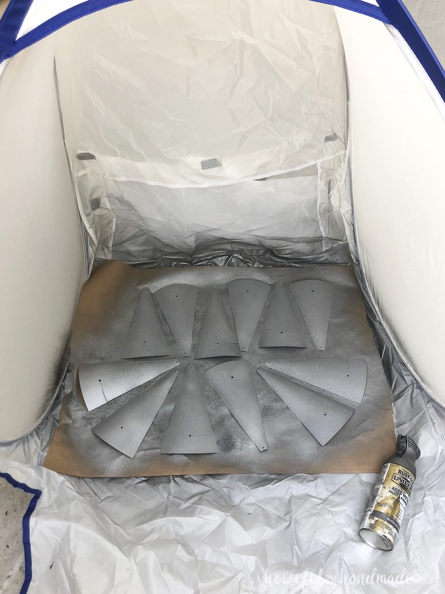 Spray painting paper fan blades with hammered metal spray paint in a spray shelter.