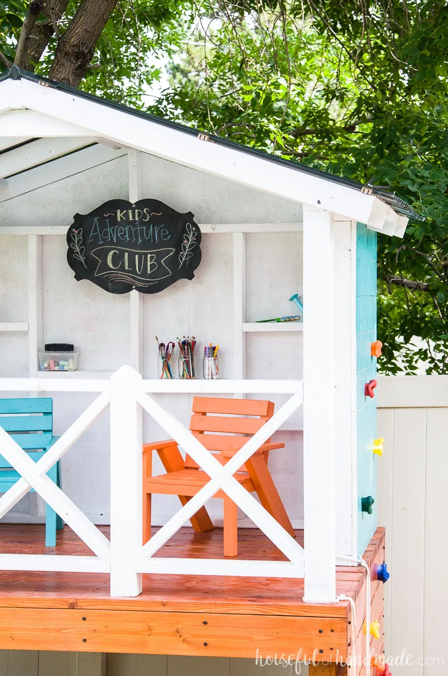 This kids playhouse is the perfect outdoor living space for any family. Orange and blue kids sized chairs inside.
