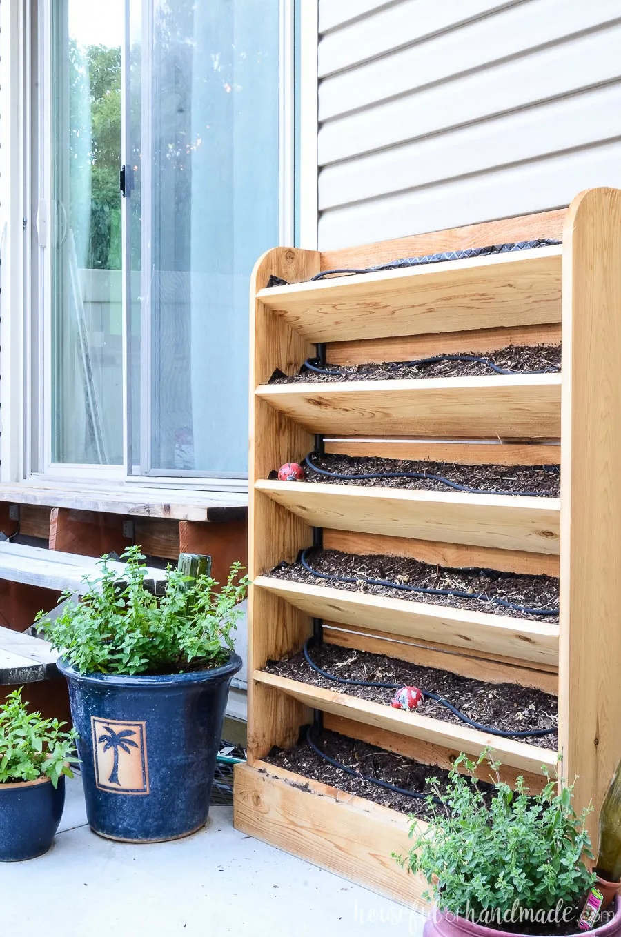 Vertical cedar herb garden and potted herbs make a great accompaniment to an outdoor kitchen area. 