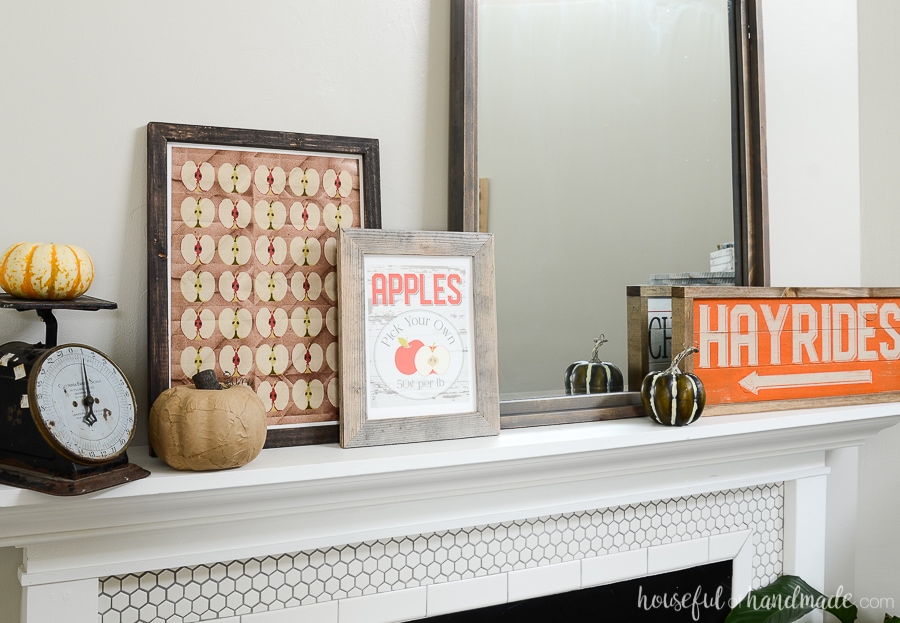 Closeup of the farmhouse styled classic fall mantel decor. Wood signs, apple picking printables and pumpkins are perfect for fall.