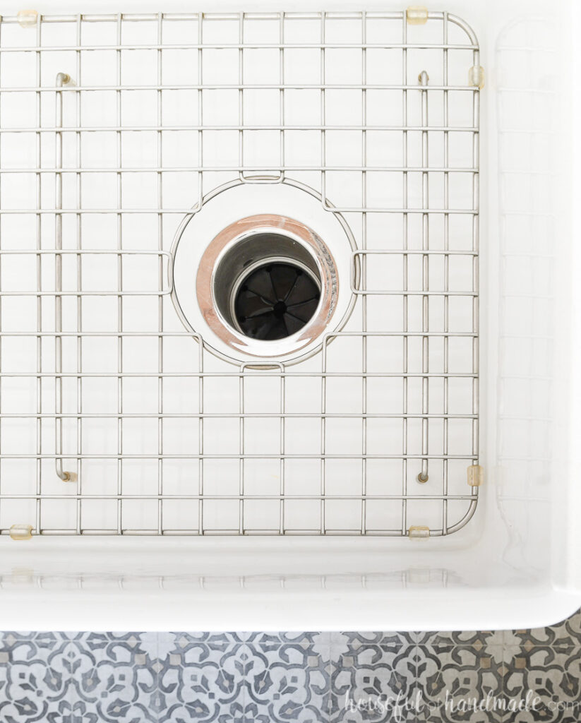Close up view of the bottom of the farmhouse sink with a sink grid in the bottom and garbage disposal in the drain.