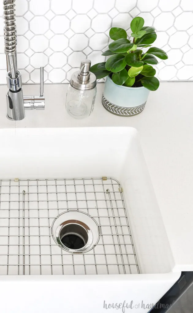 Beautiful farmhouse sink in a kitchen with white countertops and white and gray tile backsplash. 