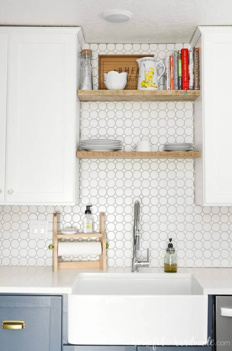 Large farmhouse sink in a kitchen with open shelving above the sink and white octagon tile backsplash. 