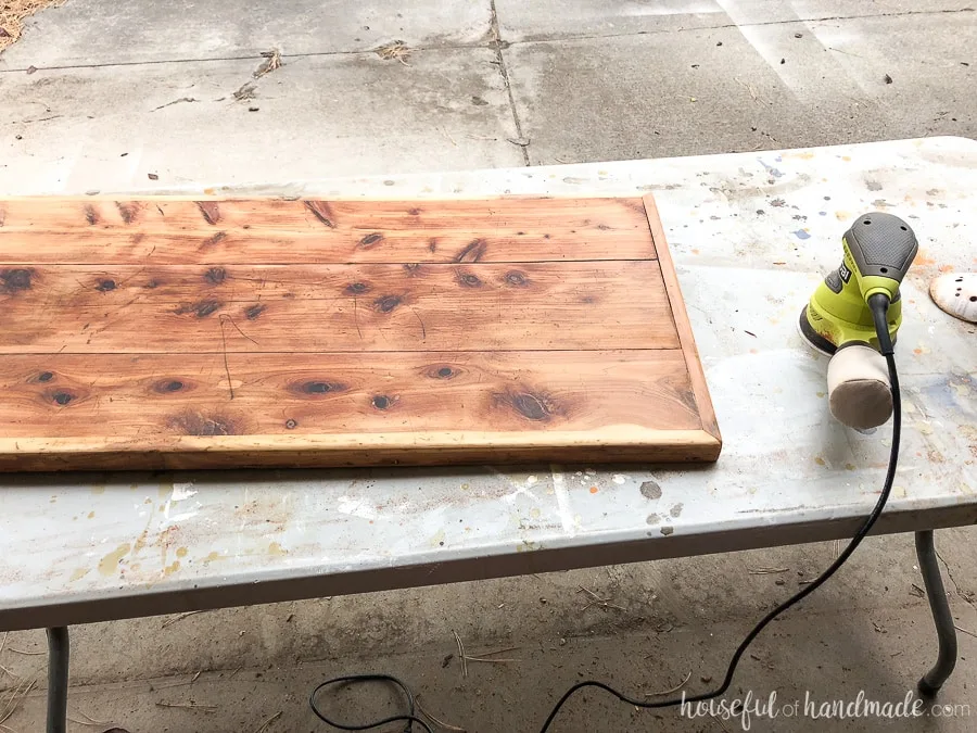 An orbital sander was used to remove the rest of the finish on the upcycled storage coffee table. 