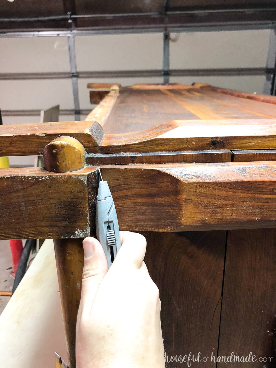 Using a utility knife to remove the bottom of the old legs to transform this chest into a coffee table. 