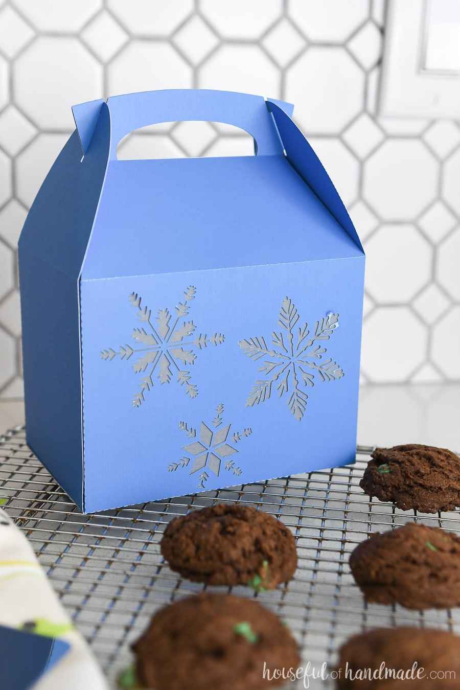 Blue Christas cookie box with snowflake design on a rack with homemade cookies. 