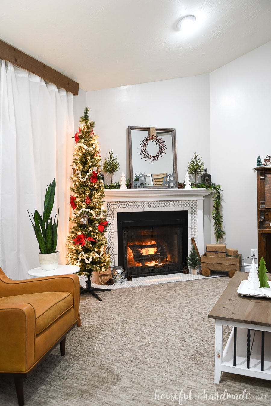 Full view of the living room decorated for the Classic Christmas home tour. Pencil tree next to the fireplace decorated with poinsettias and popcorn garland.