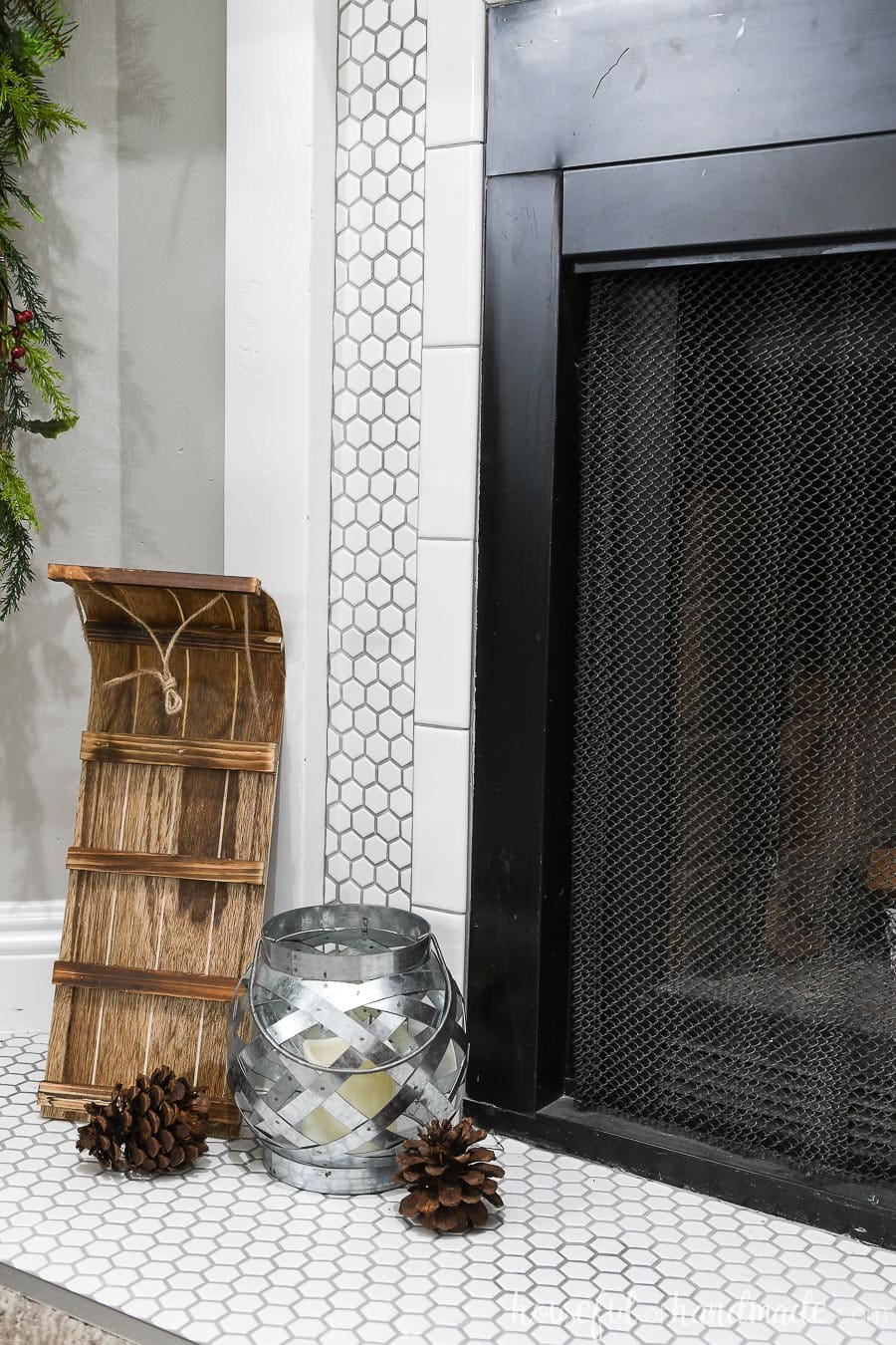 Toboggan and galvanized metal lantern on the fireplace hearth as part of the classic Christmas mantel decor. 
