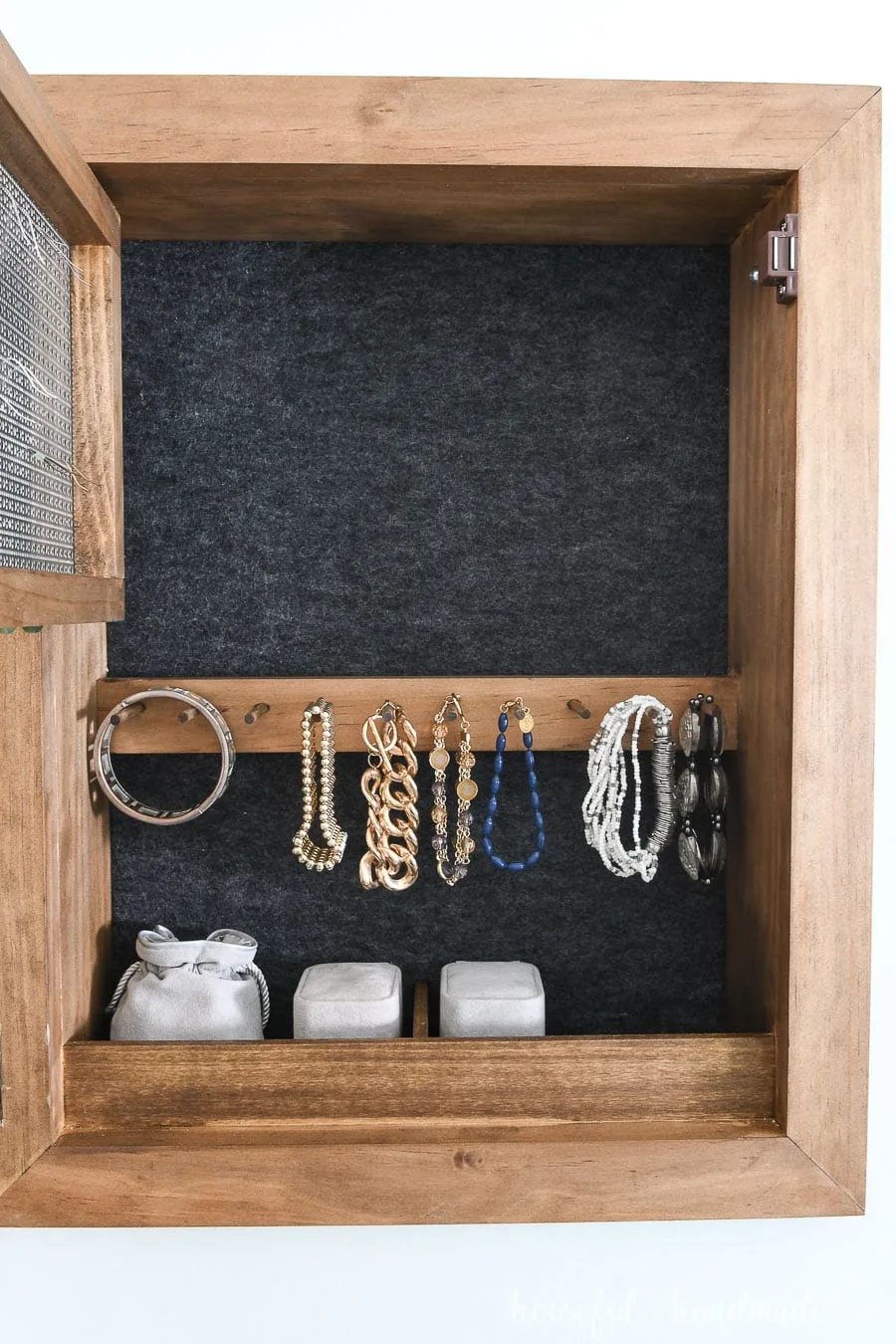 DIY jewelry cabinet opened up to see the felt back and bracelet rack.
