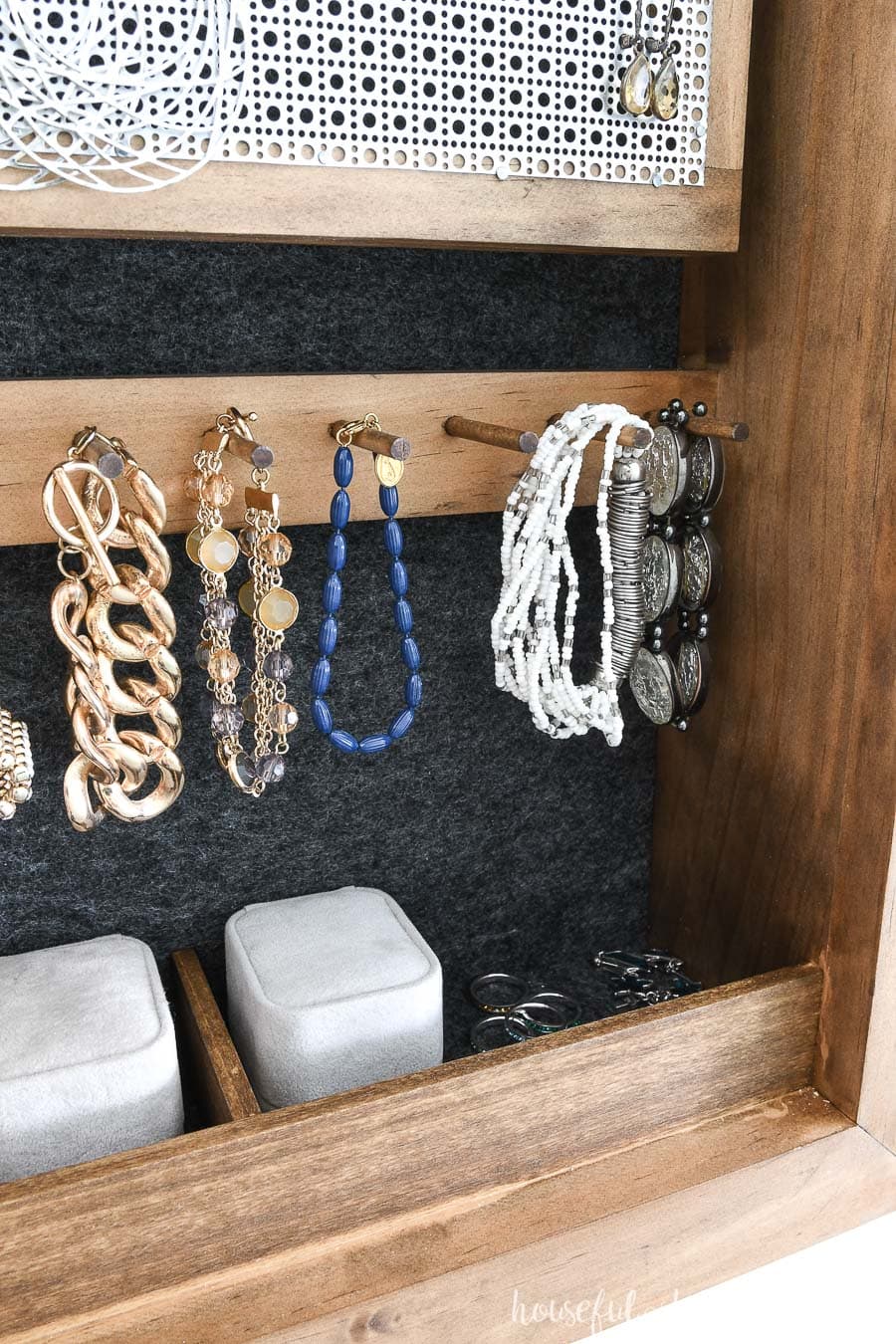 Close up view of bracelet hooks and ring compartments of the DIY wall jewelry organizer. 