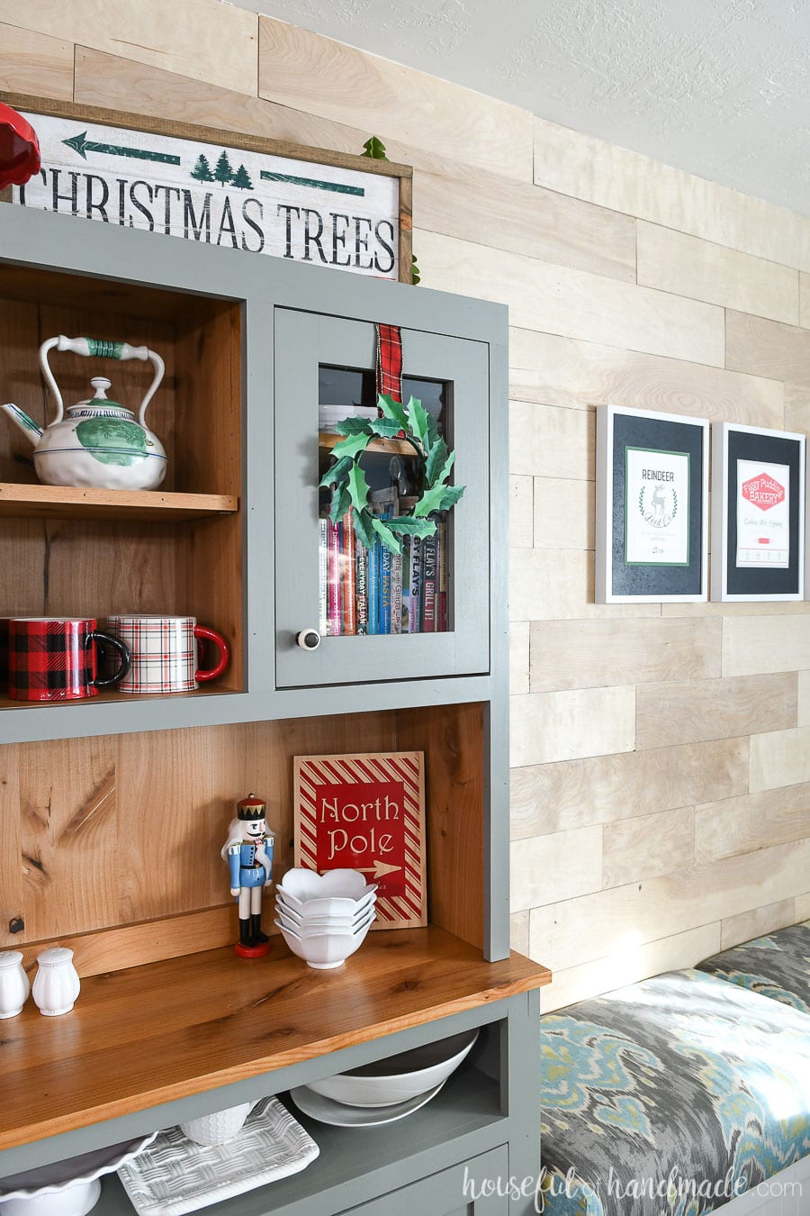 Side view of the paper holly wreath on the hutch cabinet doors with the printable Christmas signs hanging in the background.