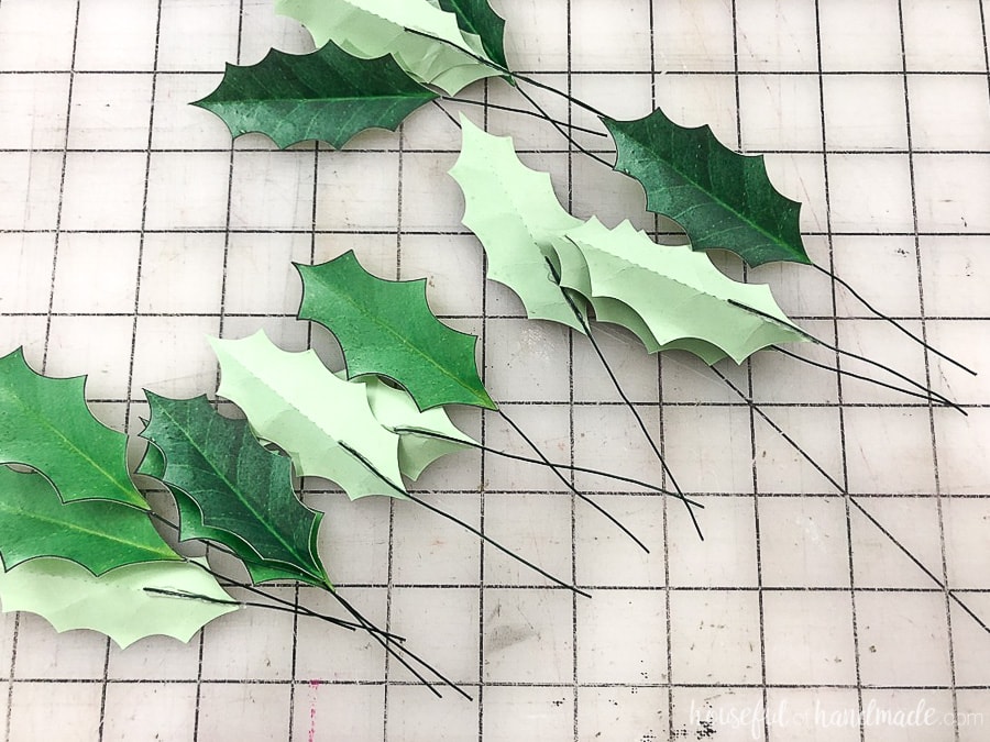 Step 2 of making paper Christmas wreaths: glue a piece of floral wire to the back of each leaf. 