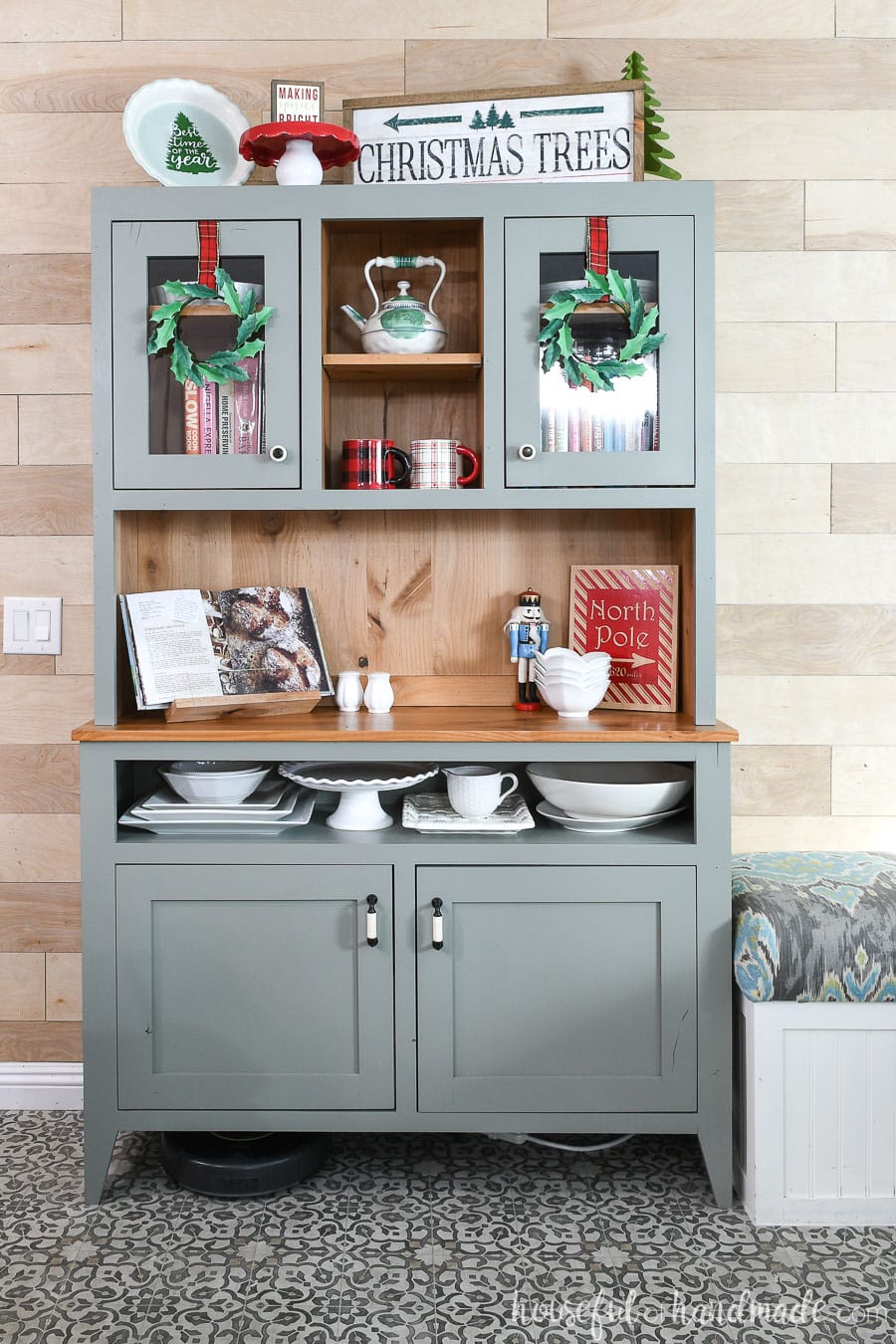 Rustic modern hutch decorated with Christmas decor and paper holly wreaths hanging on the hutch doors. 