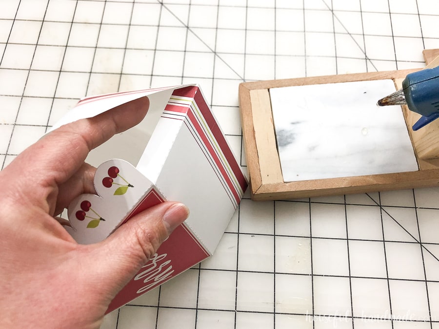 Hand holding the leftover pie box and glueing the side flaps to finish the box.