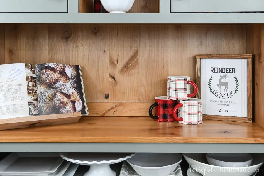 Easy DIY wood sign on the shelf of a hutch decorated for Christmas. 