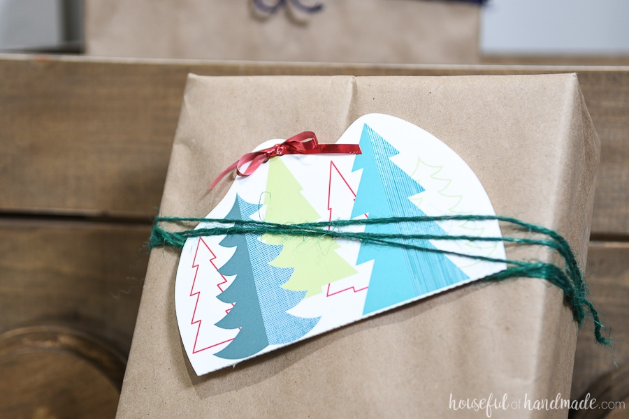 Printable Christmas gift card holder tucked into twine on the front of a present wrapped in brown packing paper.