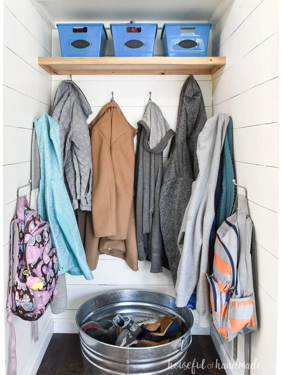 Coat closet turned into farmhouse entryway with shiplap walls and hooks for coats. 