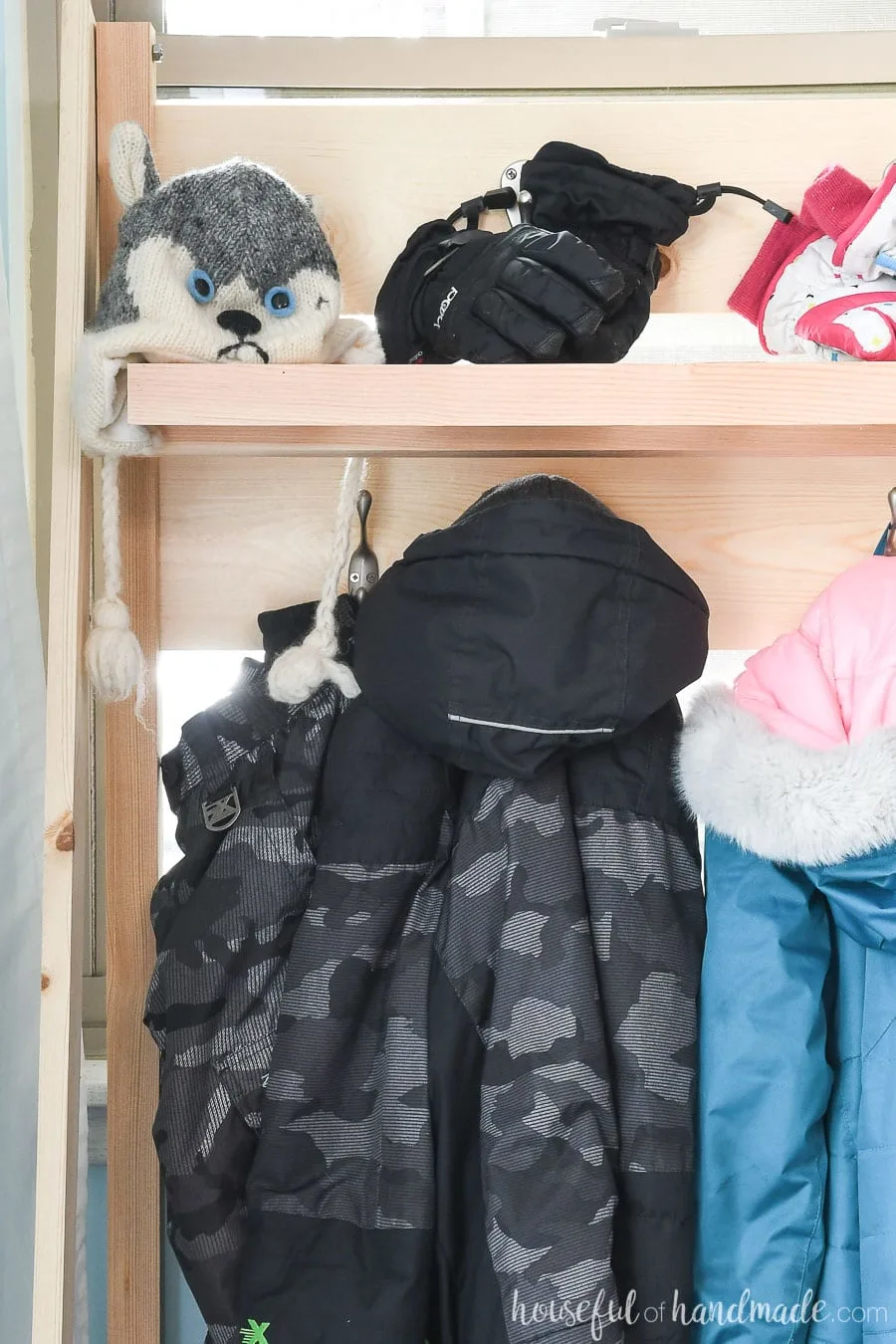 Close up of the coats hanging on the collapsible storage shelves in the mudroom. 